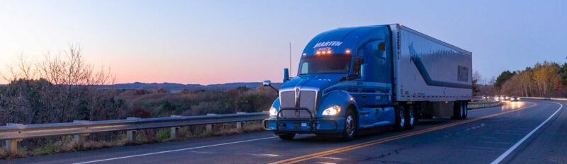 Blue Marten Truck traveling down two lane road