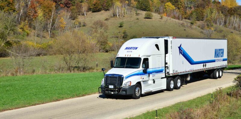 White Marten truck and trailer driving with rolling hills in background