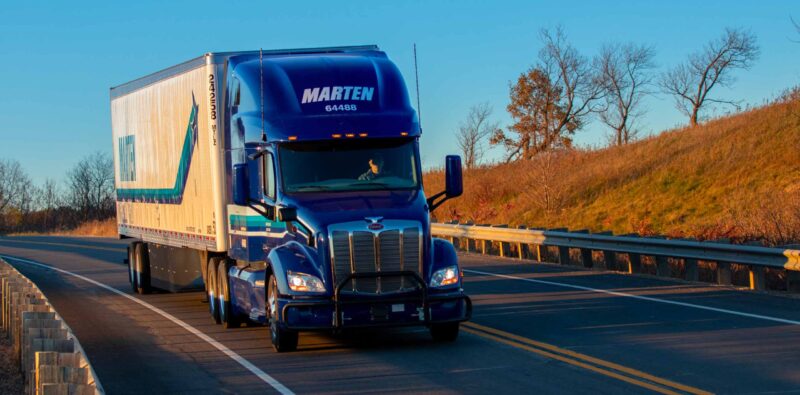Blue Marten truck and trailer driving down road in morning
