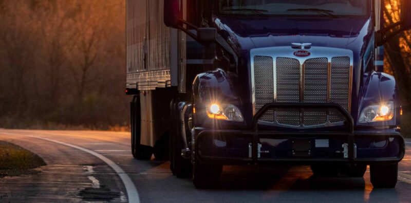 Peterbilt Marten Truck and Trailer driving down road at dusk